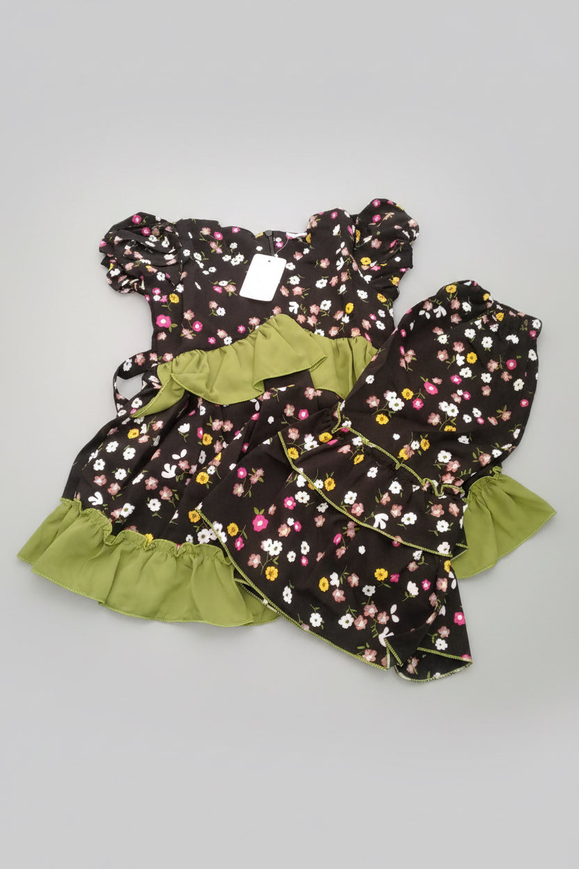Children's dress with floral pattern and green trim on a blue surface