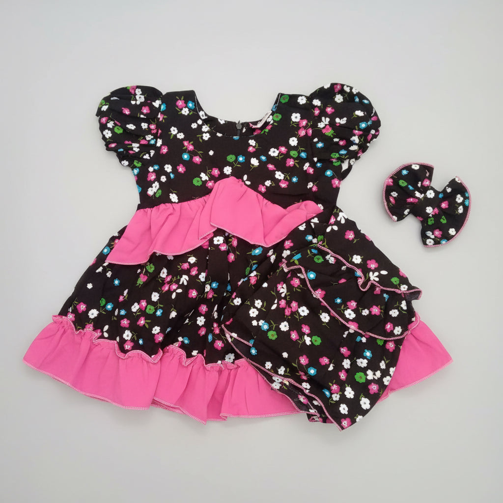Children's dress with floral pattern and pink accents on a blue surface